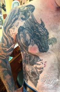 dragon and skulls on ribs tattoo